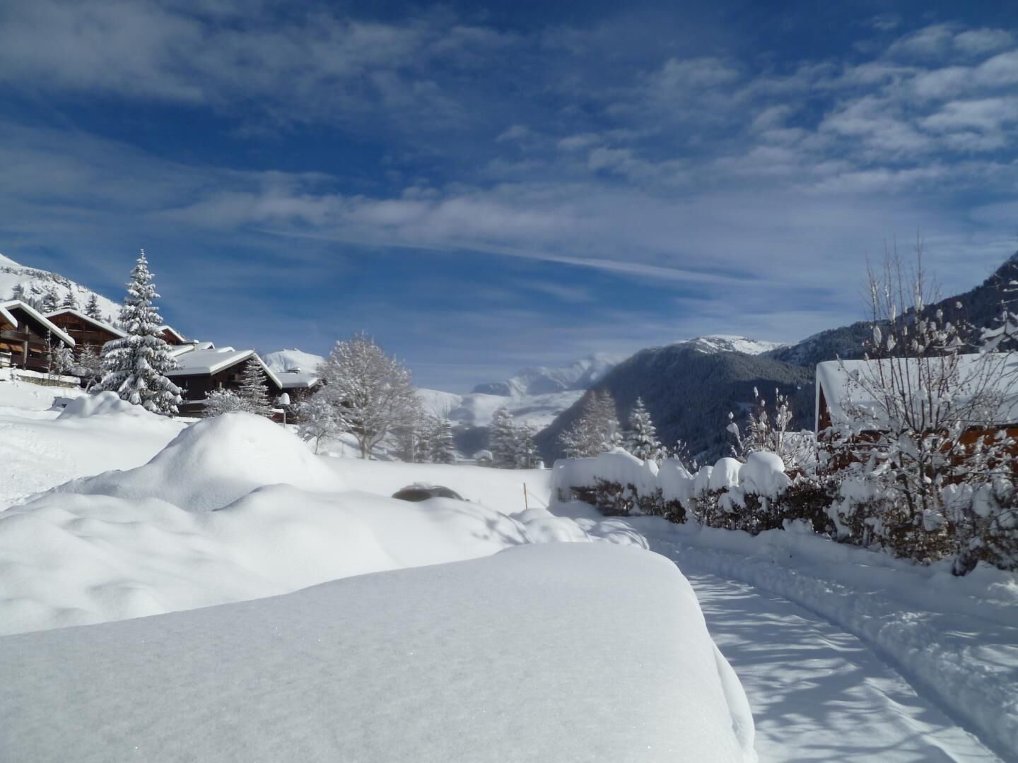 A snow-covered mountain landscape with wooden cabins and a clear sky.