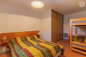 Ein Schlafzimmer mit einem hölzernen Bett, einem Etagenbett, einem Nachttisch mit Lampe und einem Kleiderschrank.