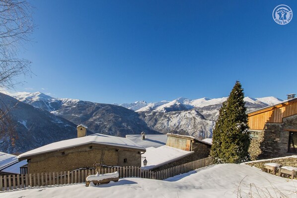 A snow-covered mountain village with traditional stone buildings and wooden fences.