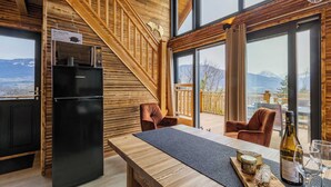 Et moderne køkken med et sort køleskab, en trætrap og et spiseområde med et bord og stole.