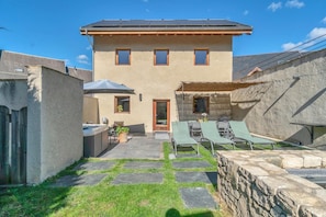 A two-story house with a patio area featuring a hot tub, outdoor seating, and a stone wall. - LA GRANGE A ROGER - MYANS (MYANS)