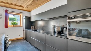 A modern kitchen with stainless steel appliances, a built-in oven, and a window with a view of greenery. - LA GRANGE A ROGER - MYANS (MYANS)
