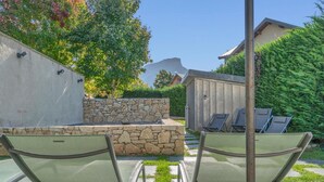 A patio area with two lounge chairs, a stone wall, and a wooden shed. - LA GRANGE A ROGER - MYANS (MYANS)
