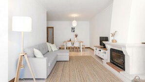 Ett modernt vardagsrum med en soffa, ett matbord, en öppen spis och en golvlampa.