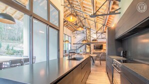 Een moderne keuken met grote ramen, een houten plafond en een centraal eiland.