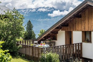 A wooden chalet with a balcony overlooking a mountainous landscape.