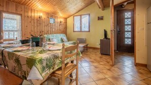 Una habitación acogedora con paredes de madera, una mesa de comedor con mantel temático tropical y una silla de madera.