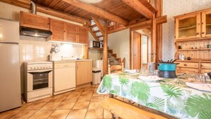 Una cocina rústica con vigas de madera, estufa, microondas y una mesa de comedor preparada para dos personas.