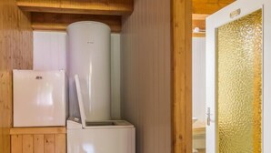A compact kitchen with a refrigerator and a sink, wooden walls, and a door with a textured glass panel. - LES MARMOTTES - LES BELLEVILLE (LES BELLEVILLE)
