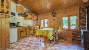 Une cabane en bois comprenant une cuisine, un coin repas et une cheminée.