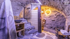 Um interior rústico de pedra com um banco de madeira, uma pia e uma porta de madeira.