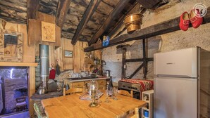Uma cozinha rústica com paredes de madeira, lareira de pedra, mesa de jantar de madeira e uma geladeira Liebherr.