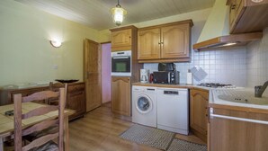 Une cuisine compacte avec des meubles de rangement en bois, un lave-linge, un four à micro-ondes et une cuisinière à gaz.
