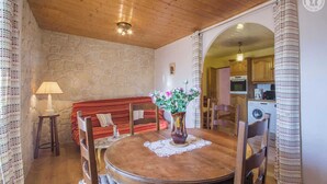 Un coin repas chaleureux avec une table ronde en bois, un mur en pierre et un plafond en bois.