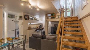 A compact living space with a kitchen, dining area, and a wooden staircase. - LA TARINE N°8 - PALLUD (PALLUD)