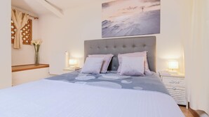 A bedroom with a large bed, two bedside tables with lamps, a wooden bench, a vase with flowers, and a painting on the wall. - LA TARINE N°8 - PALLUD (PALLUD)