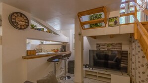 A compact living space with a kitchen area, a dining table, a sofa, a TV, and a wooden loft. - LA TARINE N°8 - PALLUD (PALLUD)