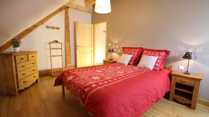 A bedroom with a wooden bed, a dresser, a ladder, and a door.