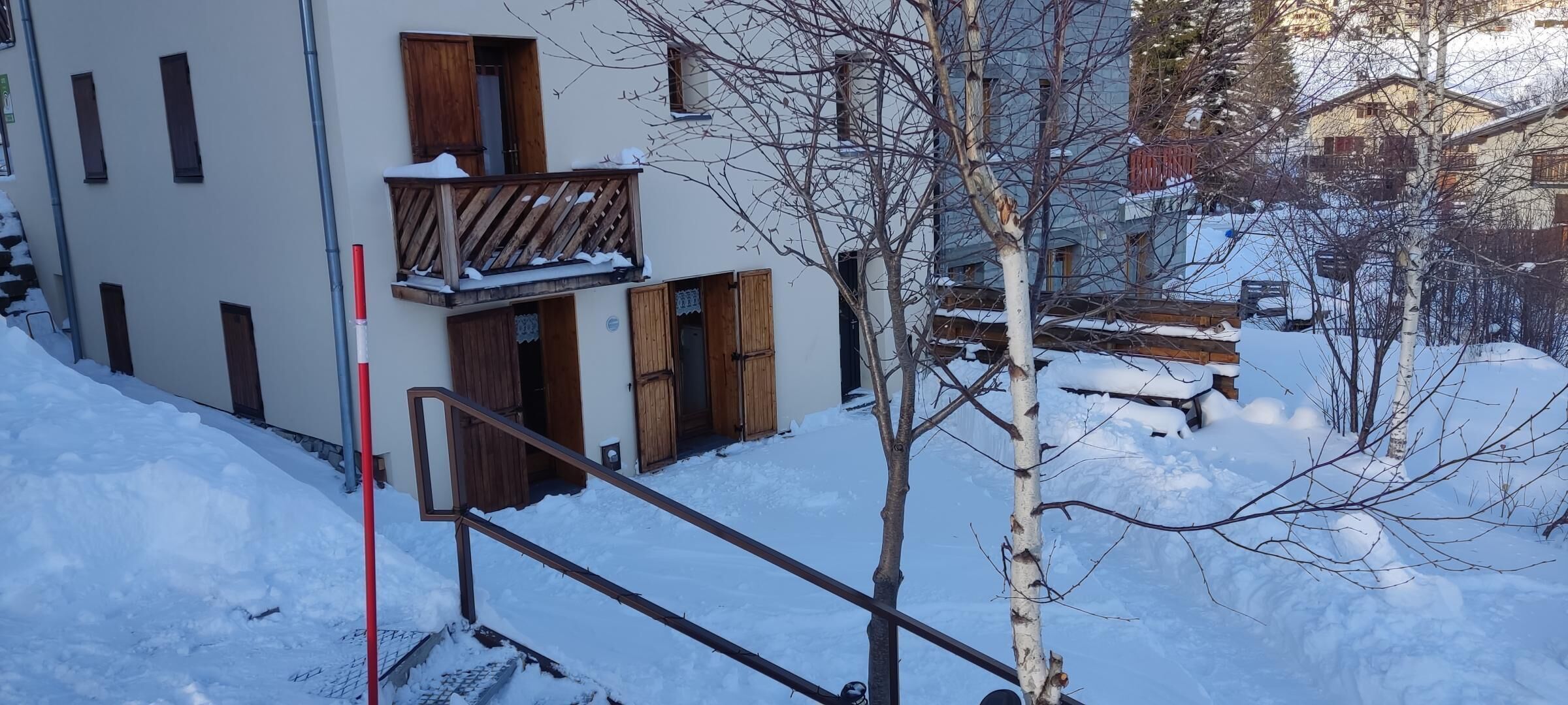 Et sneklædt hus med balkon og trædøre.
