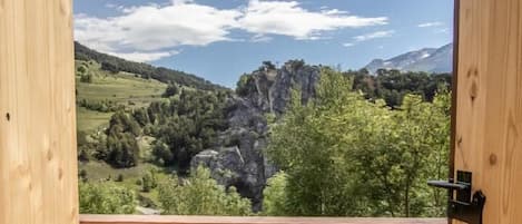 A wooden balcony with a view of a mountainous landscape and a clear sky.