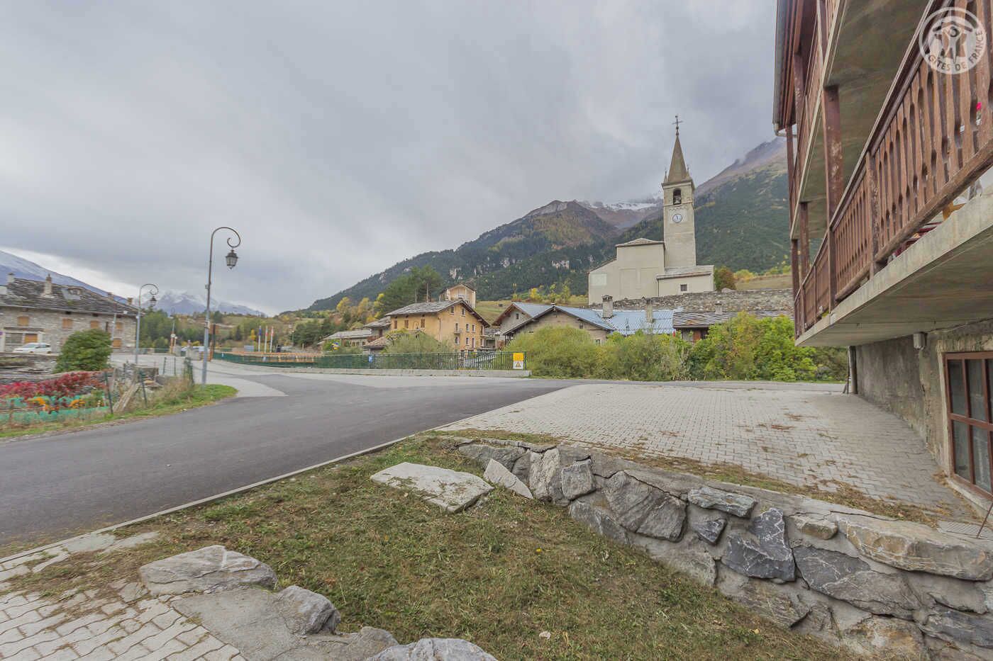A rural village with a church, stone buildings, and a mountain backdrop.