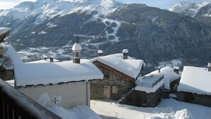 Un village de montagne enneigé, avec des bâtiments en pierre et une église.