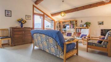 Un salon chaleureux avec un canapé, des fauteuils, une commode en bois et une bibliothèque.