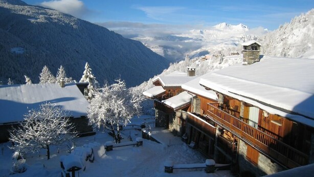 Un chalet de montagne enneigé, doté d’une architecture en bois, d’un télésiège et offrant une vue dégagée sur le paysage enneigé environnant.