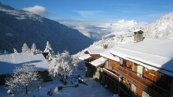 Un chalet de montagne enneigé, doté d’une architecture en bois, d’un télésiège et offrant une vue dégagée sur le paysage enneigé environnant.