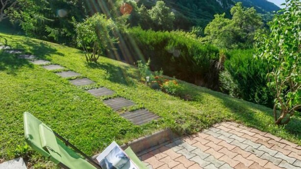 A garden with a paved area and two green chairs, a wooden table, and a mountain backdrop. - BELLE VUE - VEREL PRAGONDRAN (VEREL PRAGONDRAN)