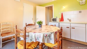 A dining area with a round table, chairs, a potted plant, a microwave, and a sink. - BELLE VUE - VEREL PRAGONDRAN (VEREL PRAGONDRAN)