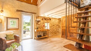 A spacious living area with a stone wall, wooden furniture, and a staircase. - LA BERGERIE - MEYRIEUX TROUET (MEYRIEUX TROUET)