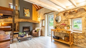 A cozy living room with a fireplace, a stone wall, a wooden coffee table, and a comfortable seating area. - LA BERGERIE - MEYRIEUX TROUET (MEYRIEUX TROUET)