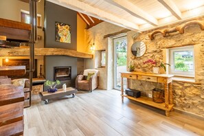 Ein gemütliches Wohnzimmer mit Kamin, Steinwand, Couchtisch aus Holz und einer komfortablen Sitzecke.