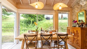 A wooden dining table with chairs, a vase with flowers, and a bottle of wine. - LA BERGERIE - MEYRIEUX TROUET (MEYRIEUX TROUET)