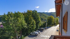 A road with cars parked on the side, surrounded by trees and a building with a sign.