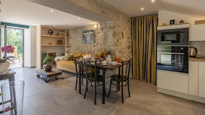 A modern kitchen with a built-in oven and a dining area with a table set for breakfast. - L'ETERNELLE - TRAIZE (TRAIZE)