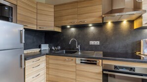 Eine moderne Küche mit Holzausstattung, Edelstahlgeräten, einer schwarzen Arbeitsplatte und einem eingebauten Backofen.