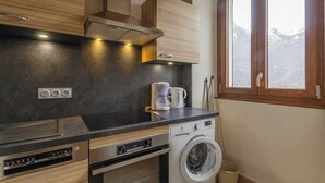 Eine kompakte Küche mit Einbauofen, Waschmaschine und Kaffeemaschine.