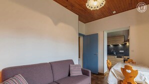 Ein modernes Wohnzimmer mit einer Couch und einem Esstisch, verbunden mit einem Küchenbereich.