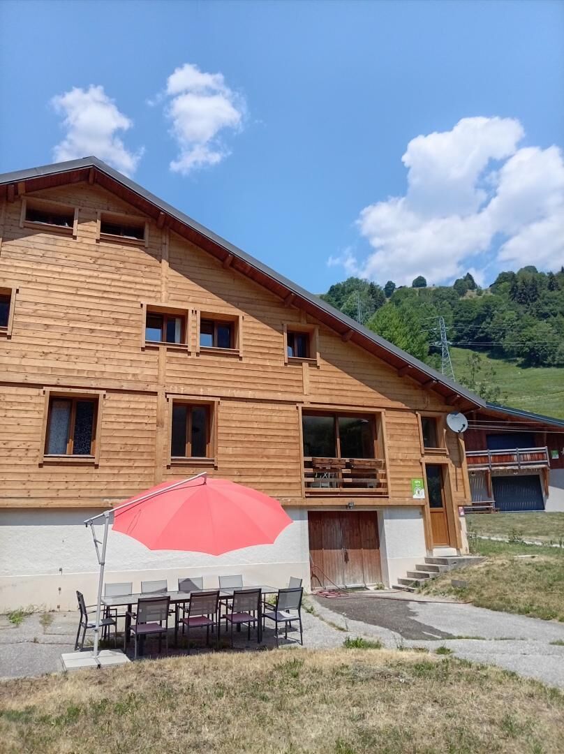 A wooden two-story building with a balcony, a covered outdoor seating area, and a satellite dish.