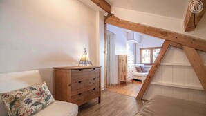 A cozy room with a wooden dresser, a white sofa, and a wooden ceiling beam. - CHALET PRANA - HAUTELUCE (HAUTELUCE)
