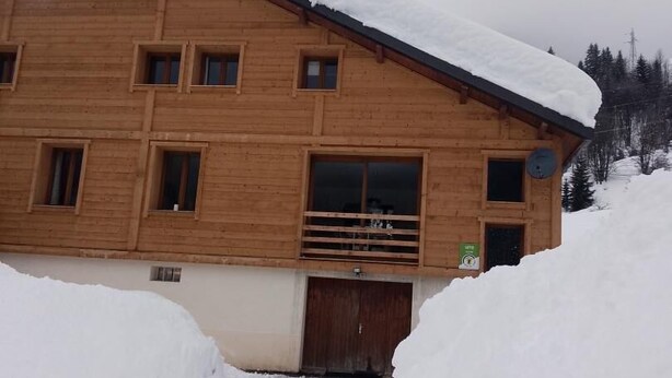 A wooden chalet with multiple windows, a balcony, and a snow-covered roof. - CHALET PRANA - HAUTELUCE (HAUTELUCE)
