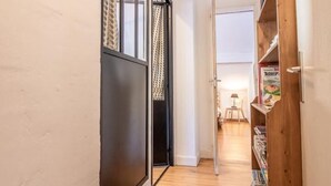 A narrow hallway with wooden flooring, a black sliding door, and a wooden bookshelf filled with books. - CHALET PRANA - HAUTELUCE (HAUTELUCE)