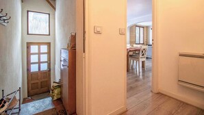 A narrow hallway with wooden flooring, a wooden door, and a small table with a chair. - CHALET PRANA - HAUTELUCE (HAUTELUCE)