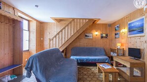 L'intérieur d'un chalet en bois, avec un canapé, un téléviseur et une petite table.