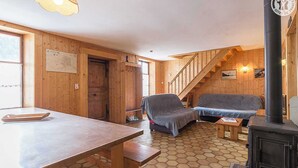 Un intérieur en bois comprenant une table à manger, un canapé, une cheminée et un escalier.