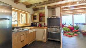 A modern kitchen with wooden cabinets, a stainless steel refrigerator, a built-in oven, and a microwave.