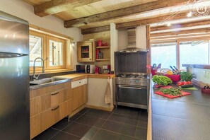 A modern kitchen with wooden cabinets, a stainless steel refrigerator, a built-in oven, and a microwave.