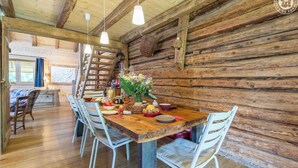 A rustic wooden dining area with a wooden table set for four, surrounded by white chairs.
